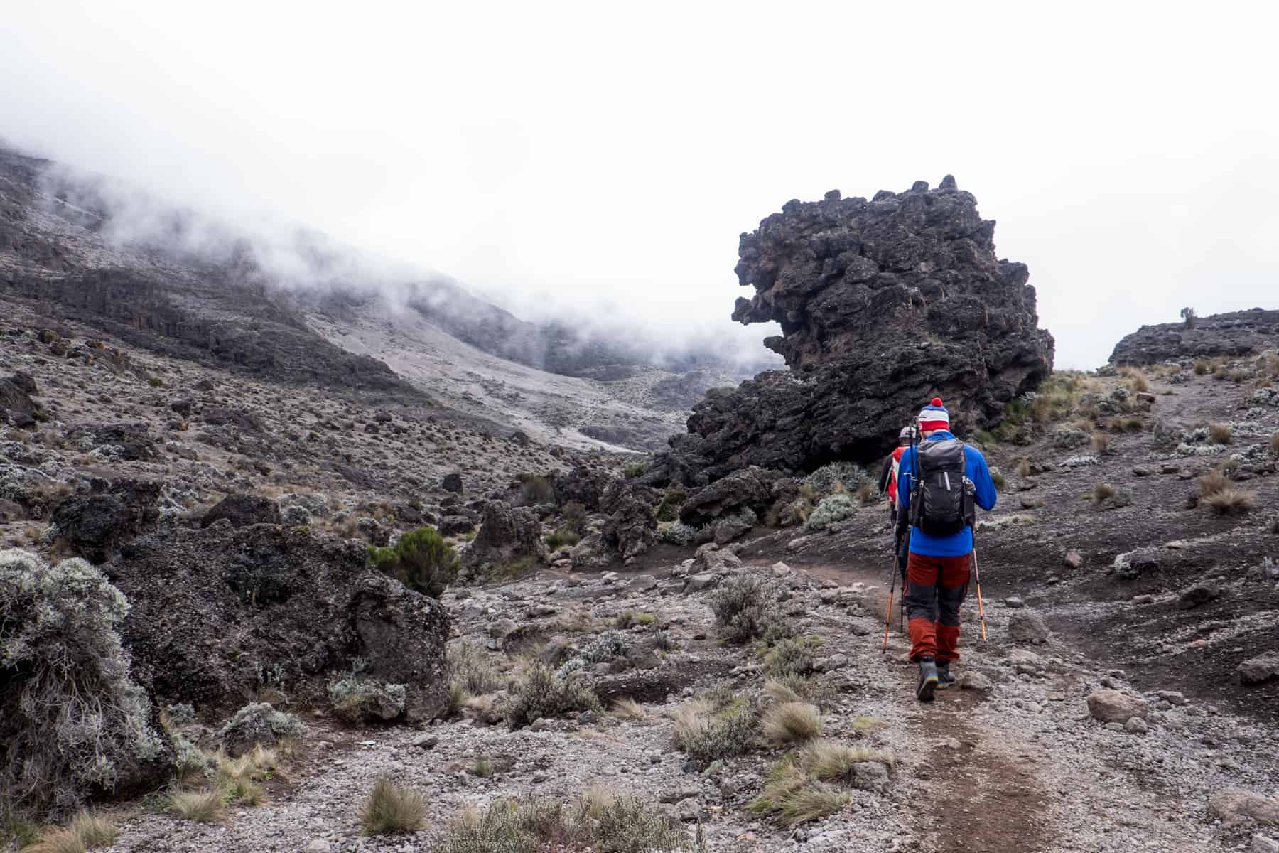 A small line of hikers on a pathway through strewn rocks and no vegetation. 