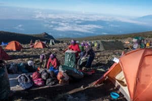 Porters on a Kilimanjaro trek packing bags at a campsite at high altitude.