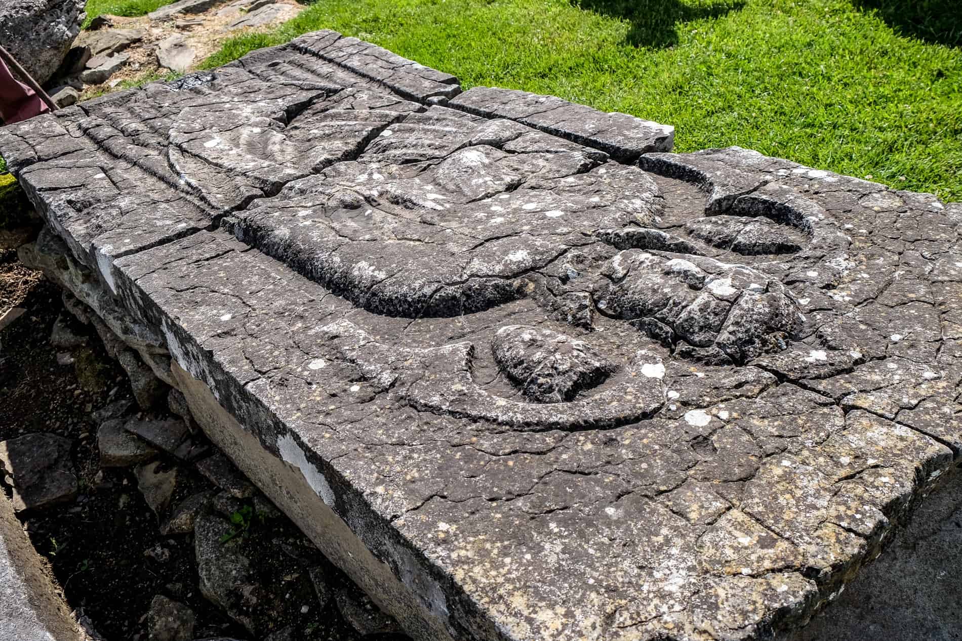 A cracked stone tomb of St. Nicholas with a carved relief of the saint. 