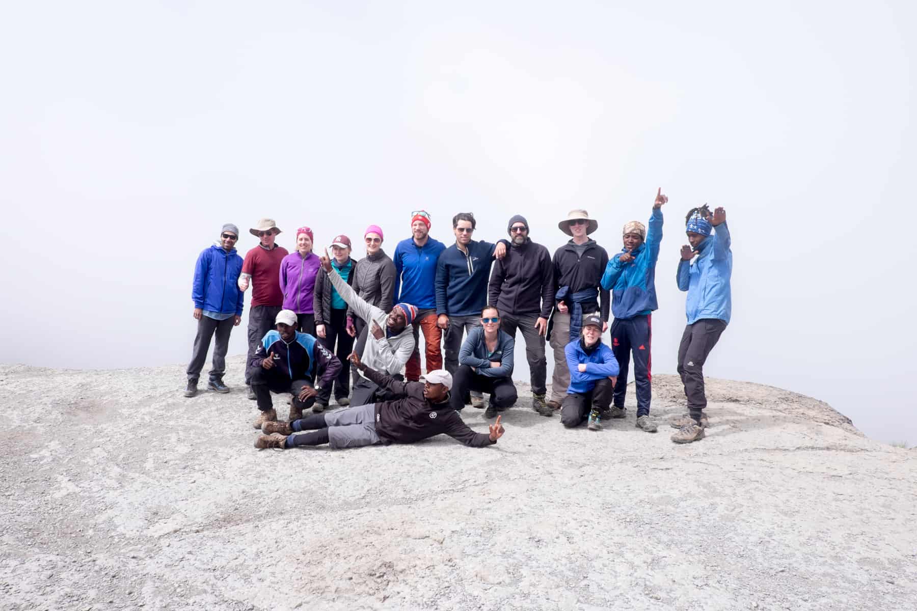 A group of trekkers posing for a photos at the top of a cloud covered rock, when climbing Kilimanjaro