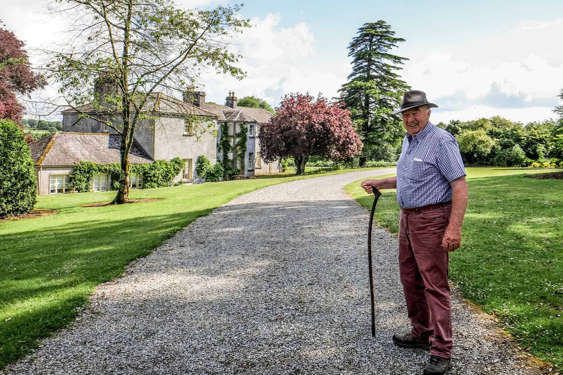 Land owner, Joe O'Connor on a gravel path in front of a farm house on the grounds of Jerpoint Park. 