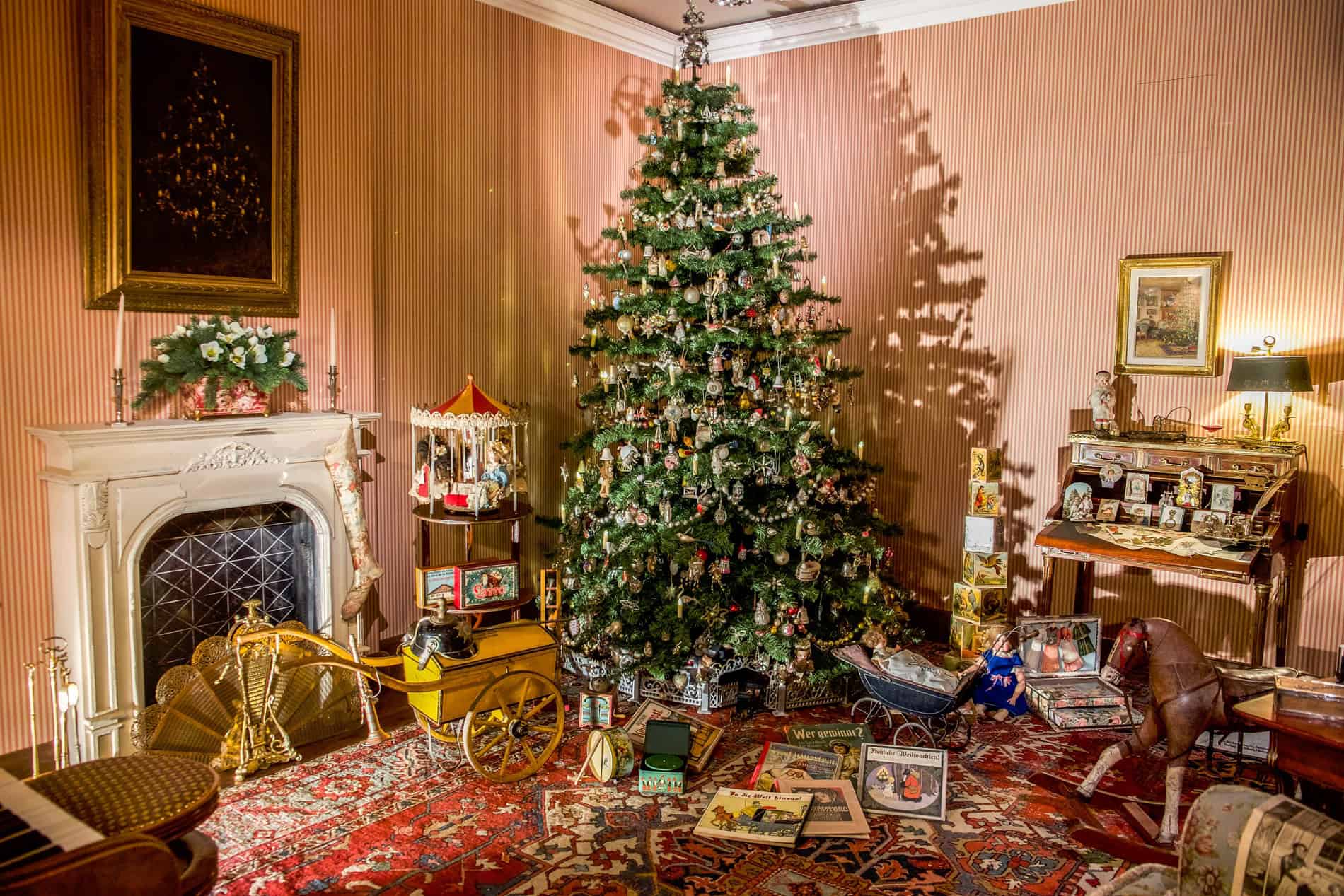 The Family Christmas exhibit at the Christmas Museum in Salzburg shows a dated living room, a large decorated Christmas tree surrounded children's toys and books.
