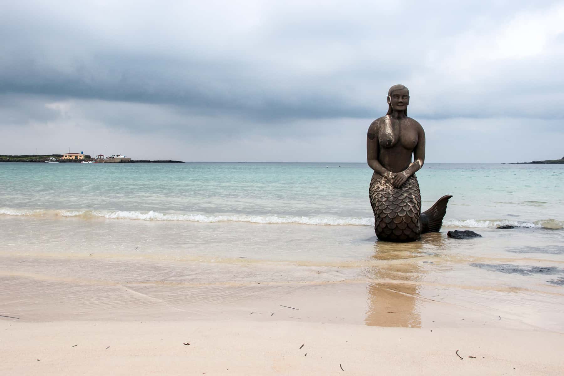 A stone Mermaid statue on the white sand beach Jeju Island coastline