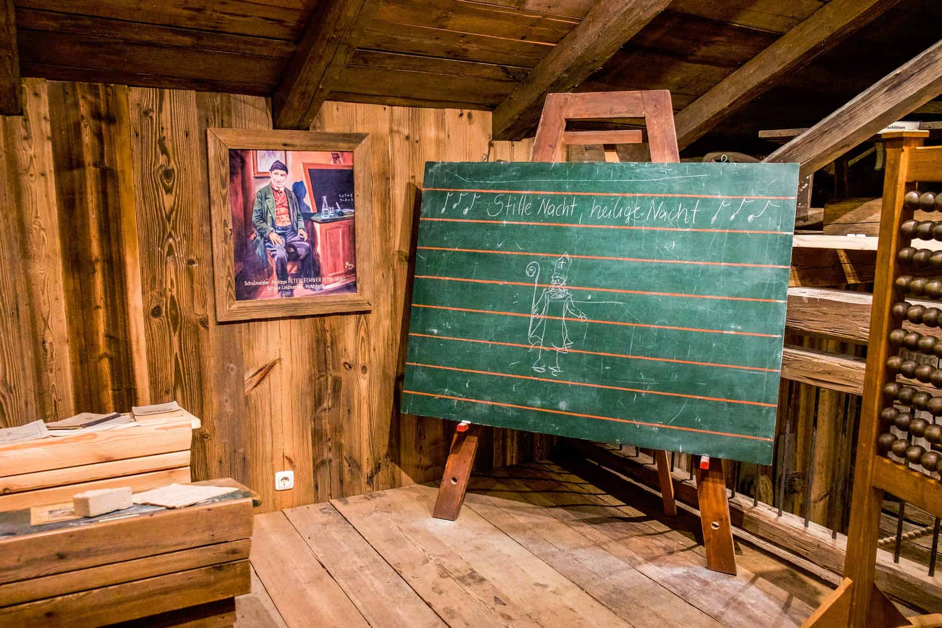 A wall portrait and green school chalk board inside a wooden house belonging to Silent Night Composer, Franz Xaver Gruber.