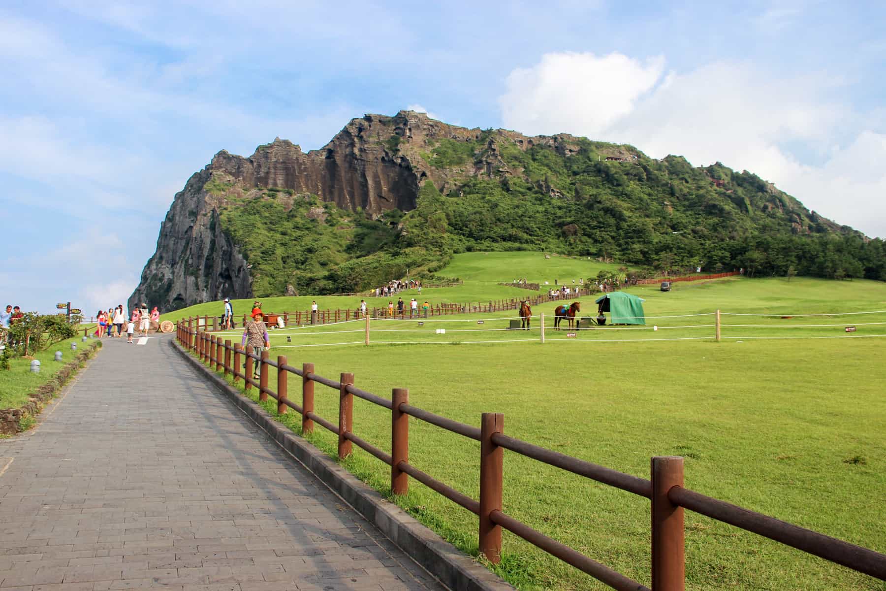 Ver olhando para um longo caminho vermelho, com trilhos que leva para o verde e o marrom vulcânica do monte Seongsan ilchulbong em Jeju Island