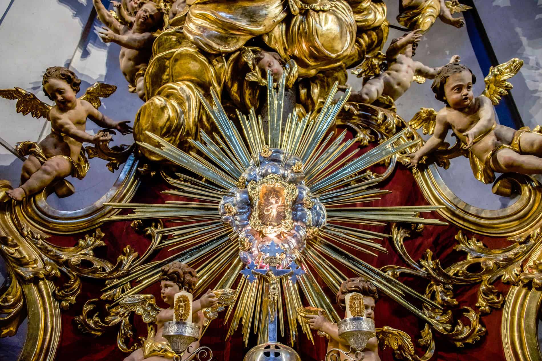 A close up of a Wax Jesus Shrine surrounded by gold decor and cherub sculptures in the famed Christkindl church in Austria. 