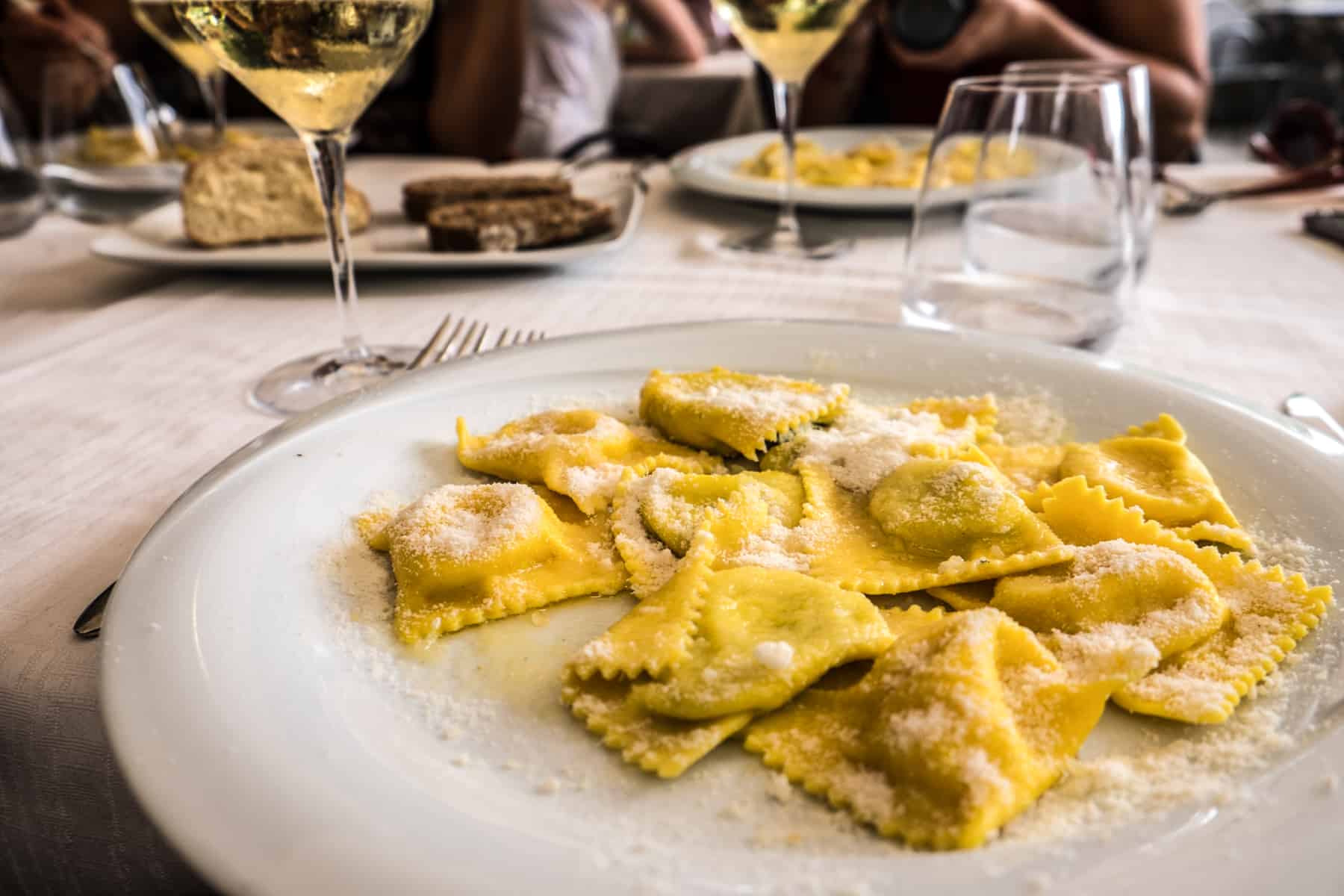 Fresh egg yellow Ravioli pasta served on a white plate with a glass of white wine in the Emilia Romagna food region in northern Italy.