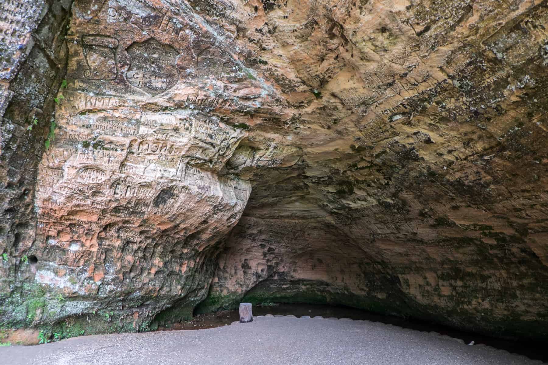 The inside of a cave covered floor to ceiling with carved inscriptions. 