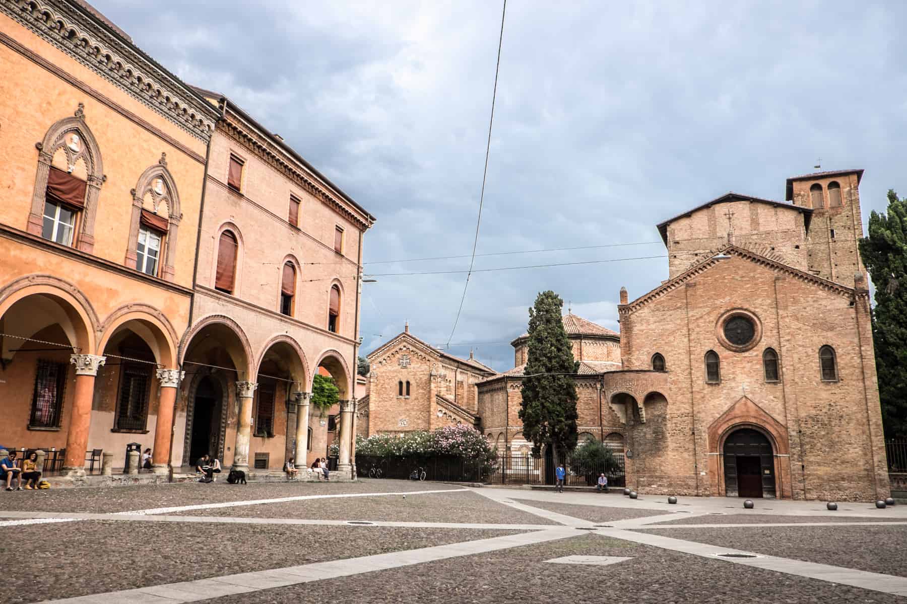 Orange and pink Palazzos to the left and the brown Basilica of Santo Stefano to the right, in Bologna's Piazza Santo Stefano.