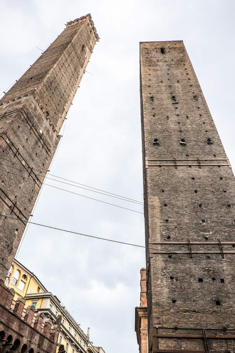The medieval stone structures of the twin towers of Bologna, that reach into the sky above the city's other buildings. 