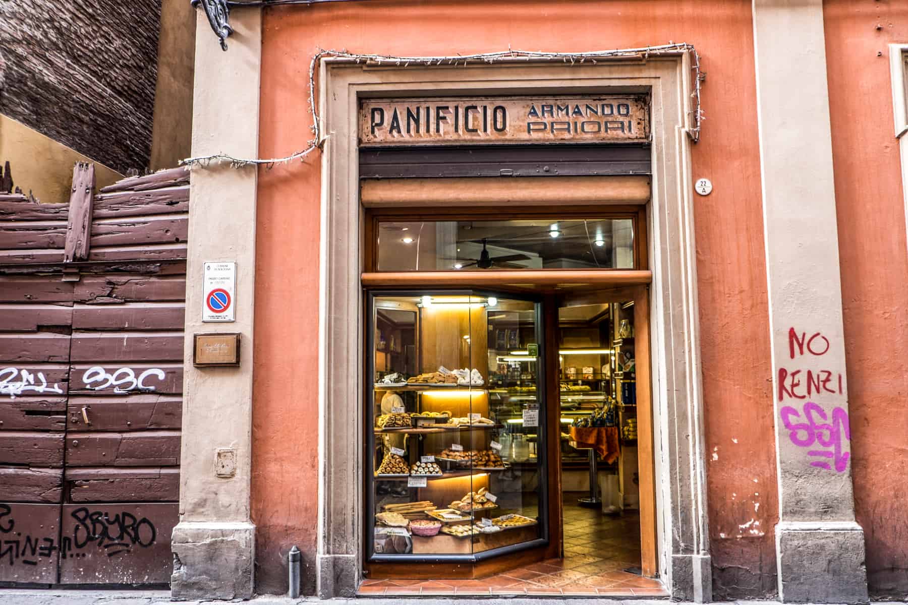 Entrance to a traditional bakery in Bologna on an orange wall, with a sign reading: "Panificio Armando Paiori".