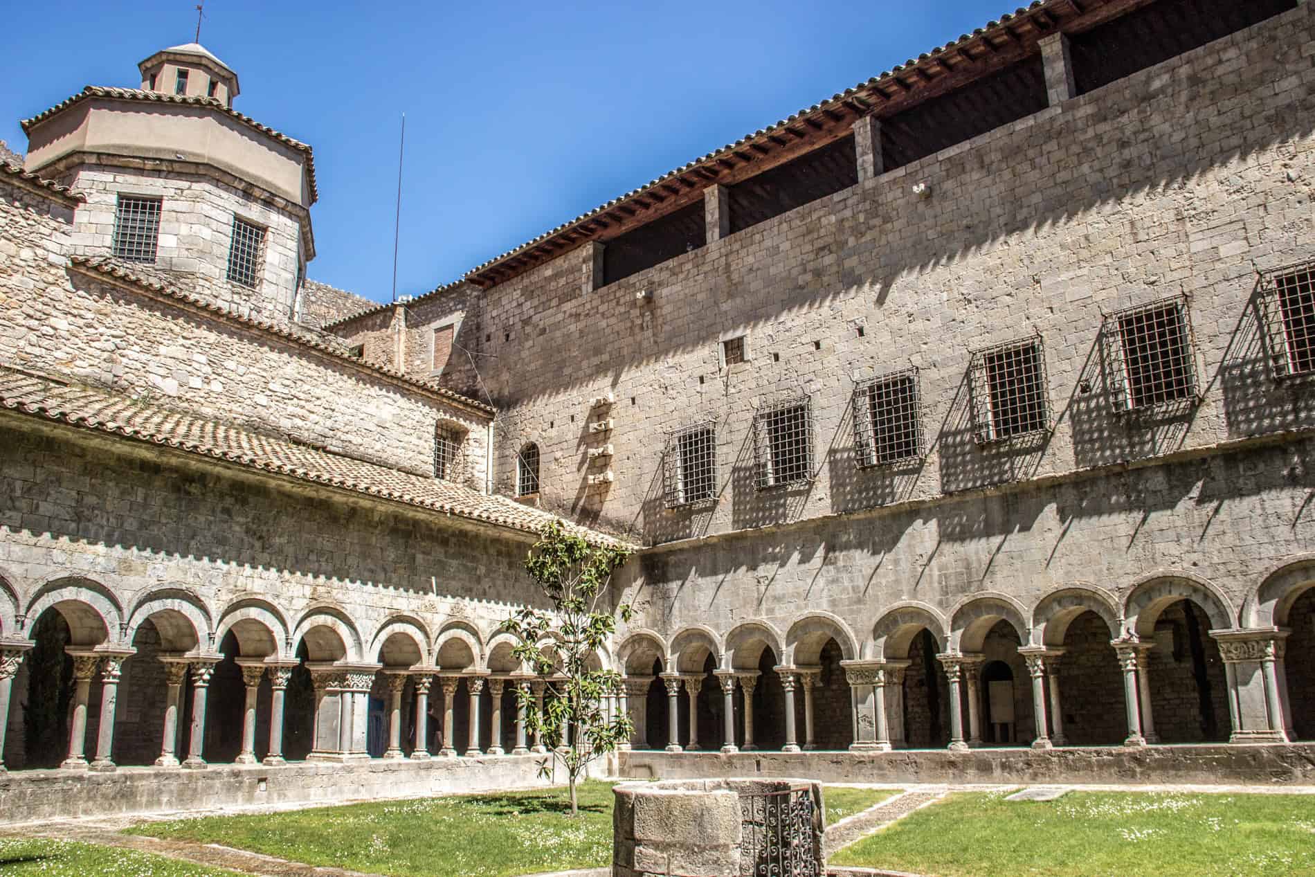 View to the green lawn courtyard of an old stone, arched Arab Bath complex in Girona. 