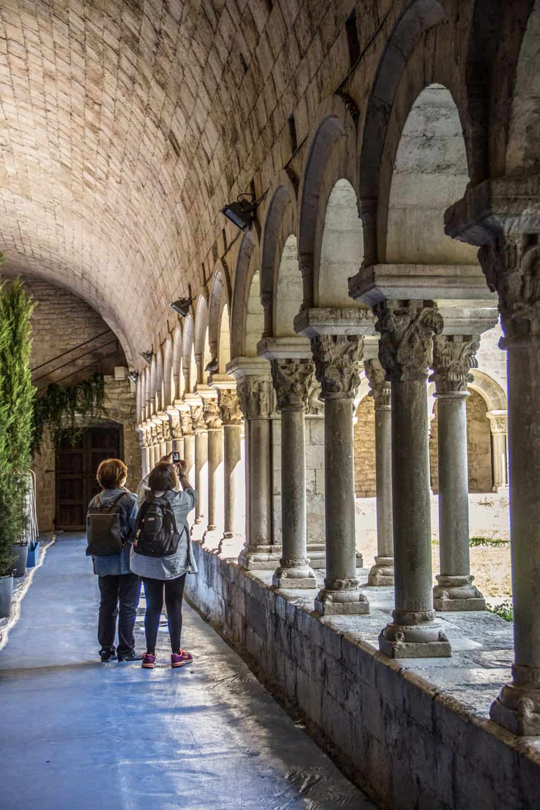 Two women photographing the stone arch colonnade in the Arab Baths of Girona. 