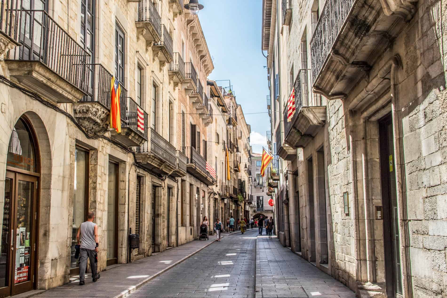 People walking in the old stone building streets of Girona. 