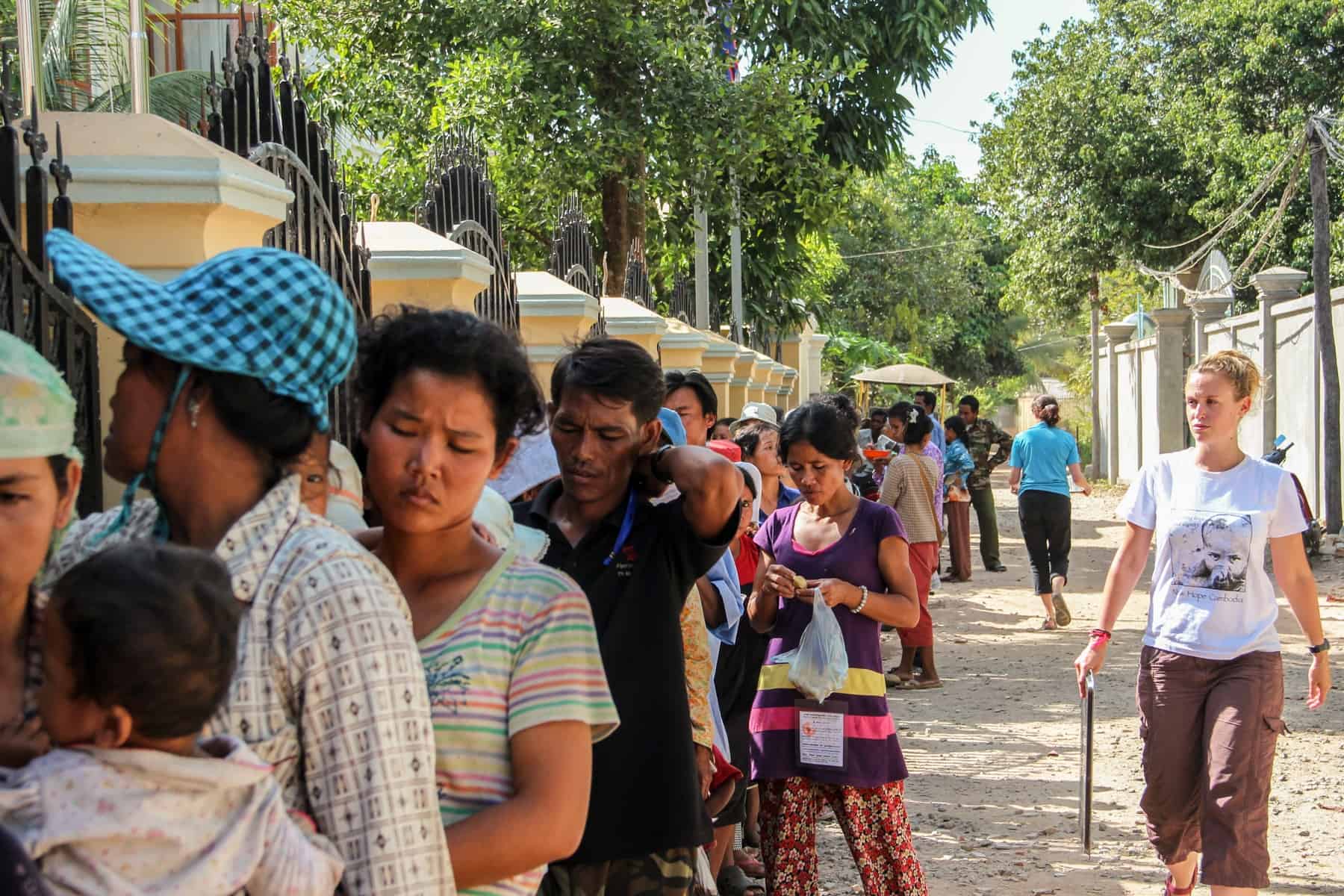 A woman walks alongside a long line of local people in Cambodia. 