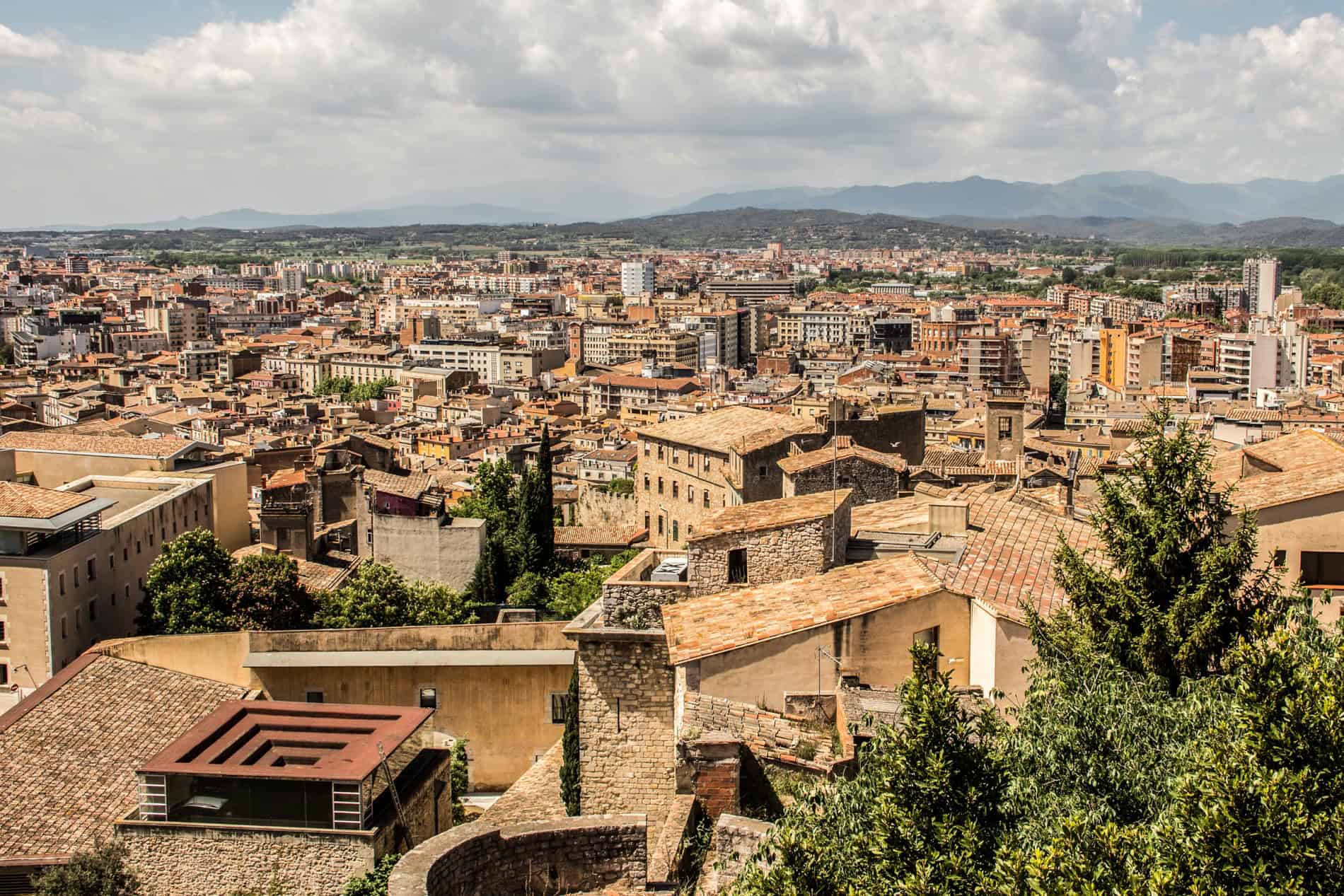 View over the cluster of orange hued buildings of Old Girona city. 