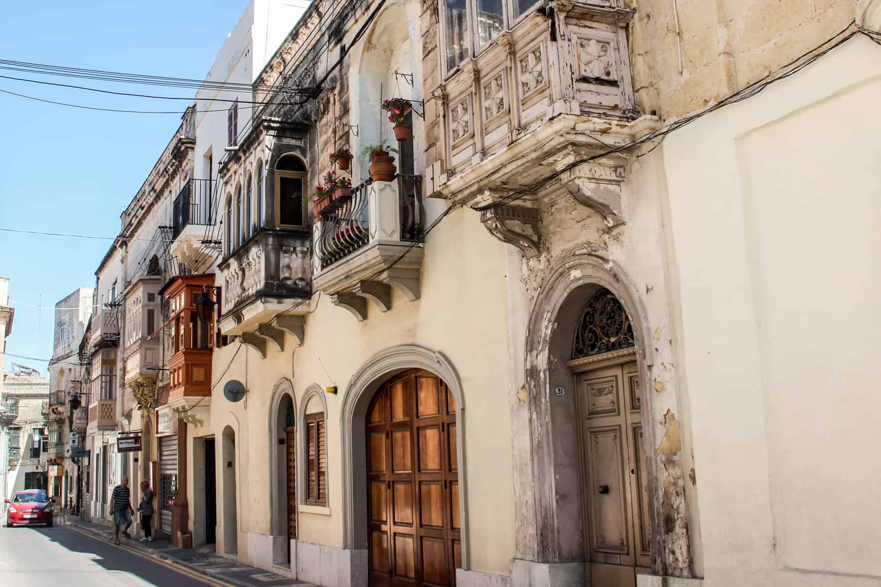 A row of beige stone houses with wooden doors and balconies. 