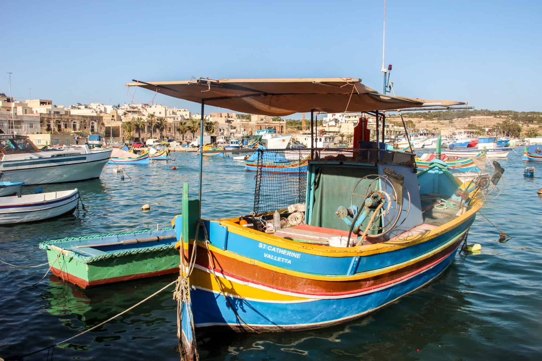 A boat painted in yellow, blue and ochre red stripes in Marsaxlokk Fishing Village, Malta. 