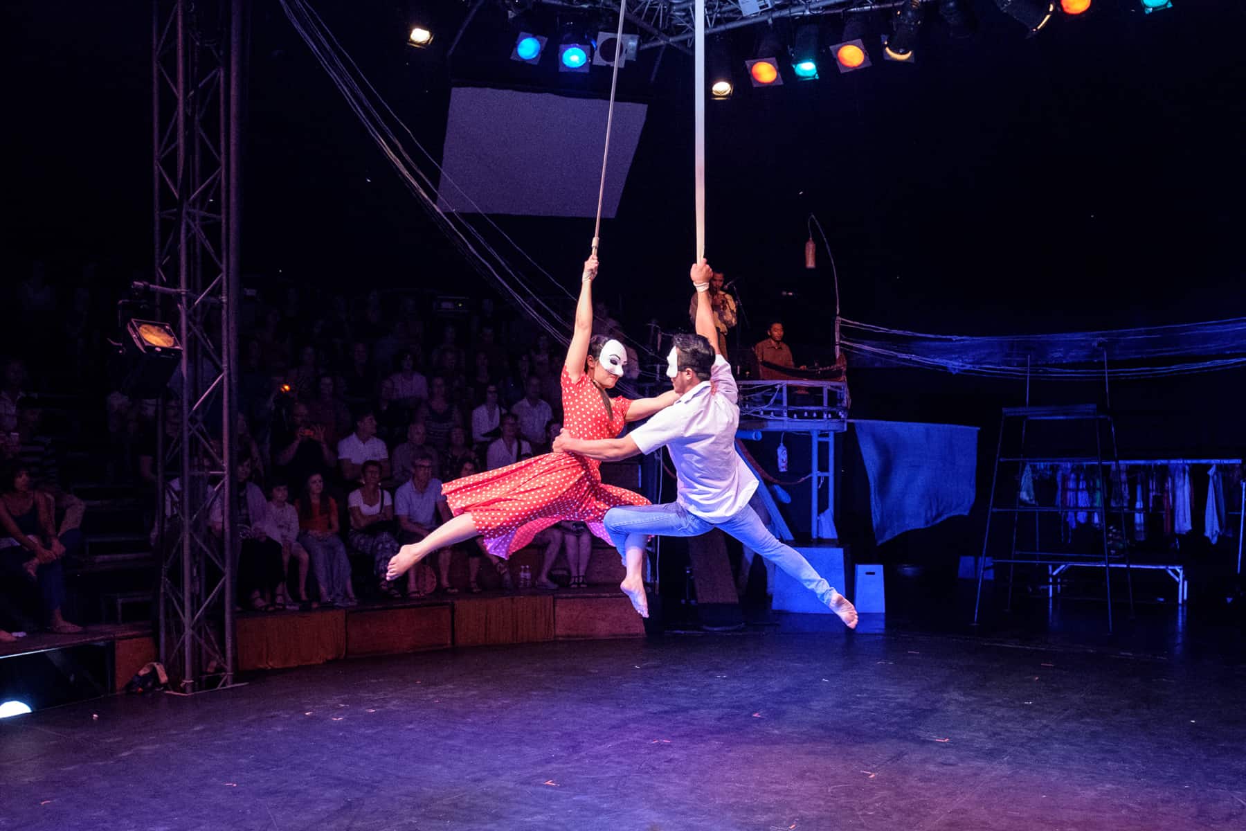 A man and woman perform a dance mid-air hanging off a suspended rope.