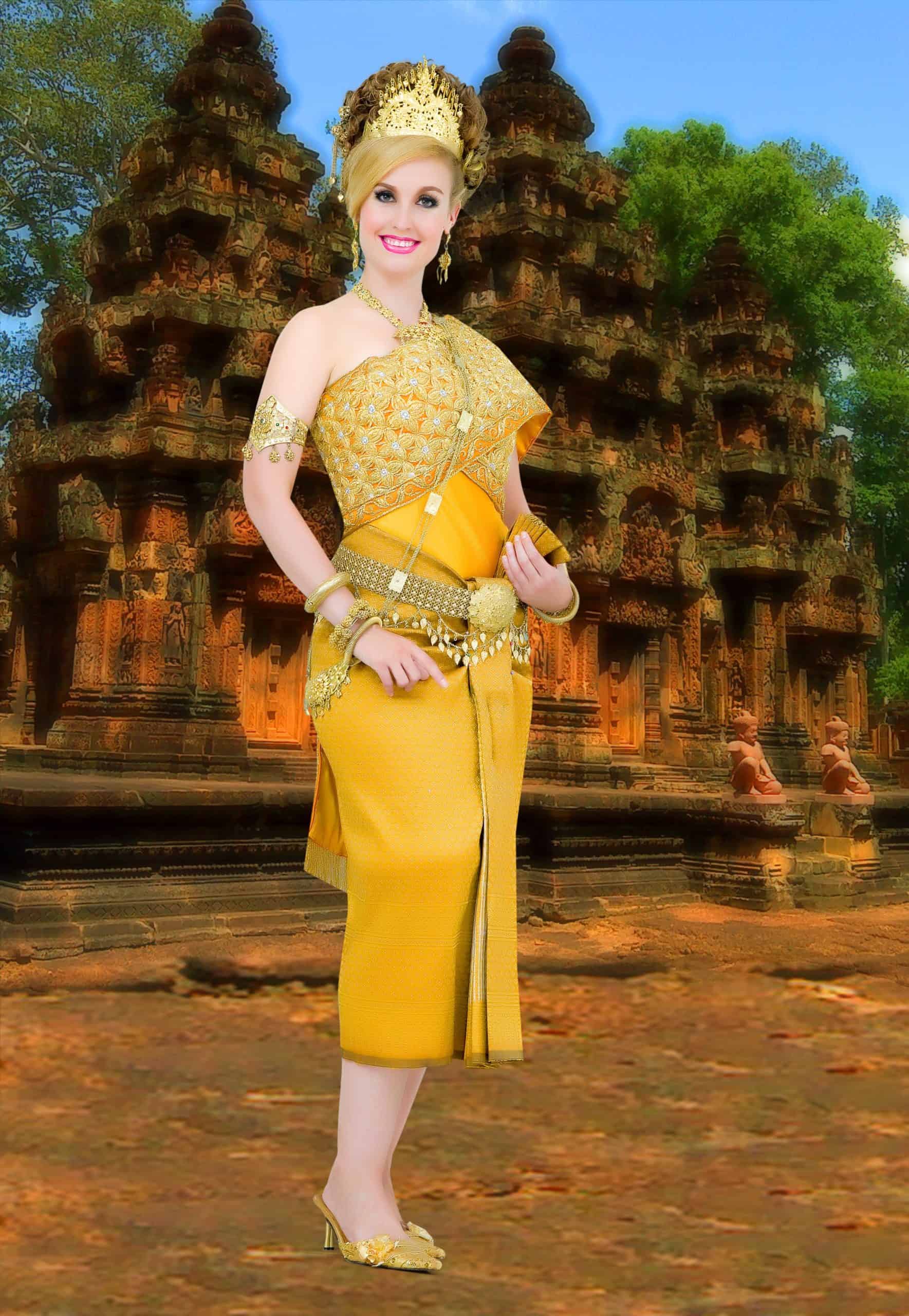 A woman wearing a traditional Cambodian outfit made of gold fabrics, chains, beading, shoes and matching gold hair piece, stands in front of a superimposed image of Angkor Wat.