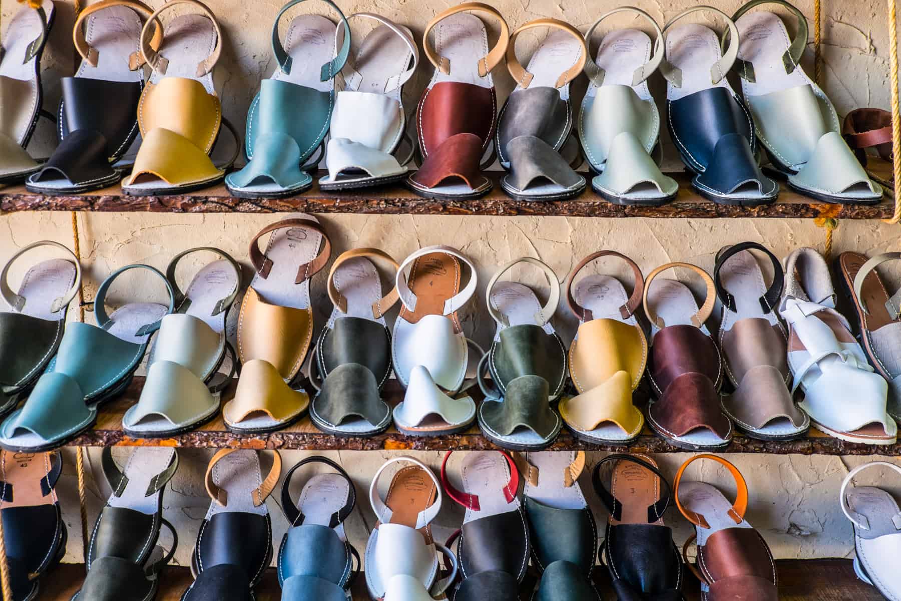 Three shelves with rows of famous Menorcan sandals in a multitude of colours. 
