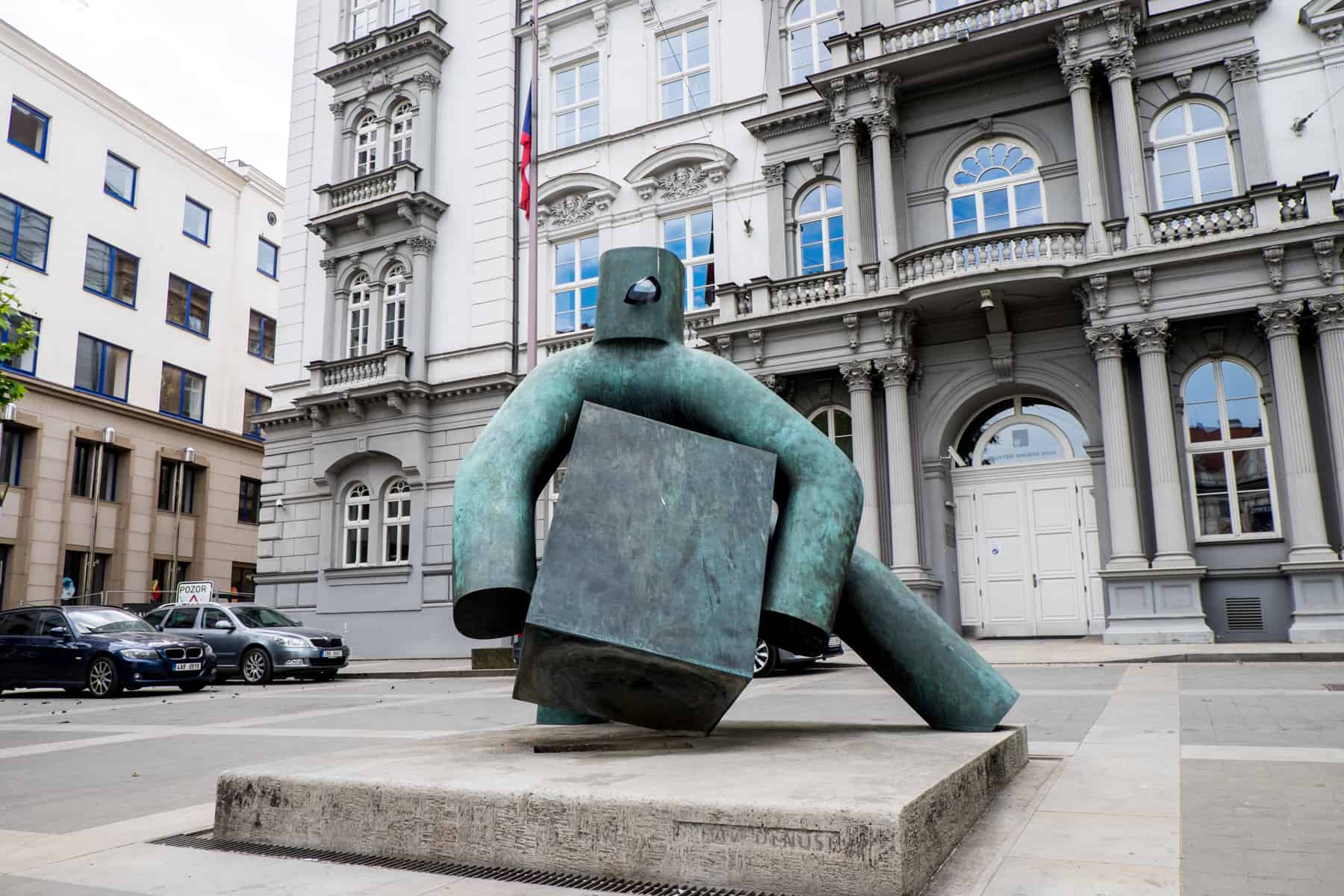 A metal sculpture of a faceless figure carrying a heavy box in Brno - seen as presenting justice. 