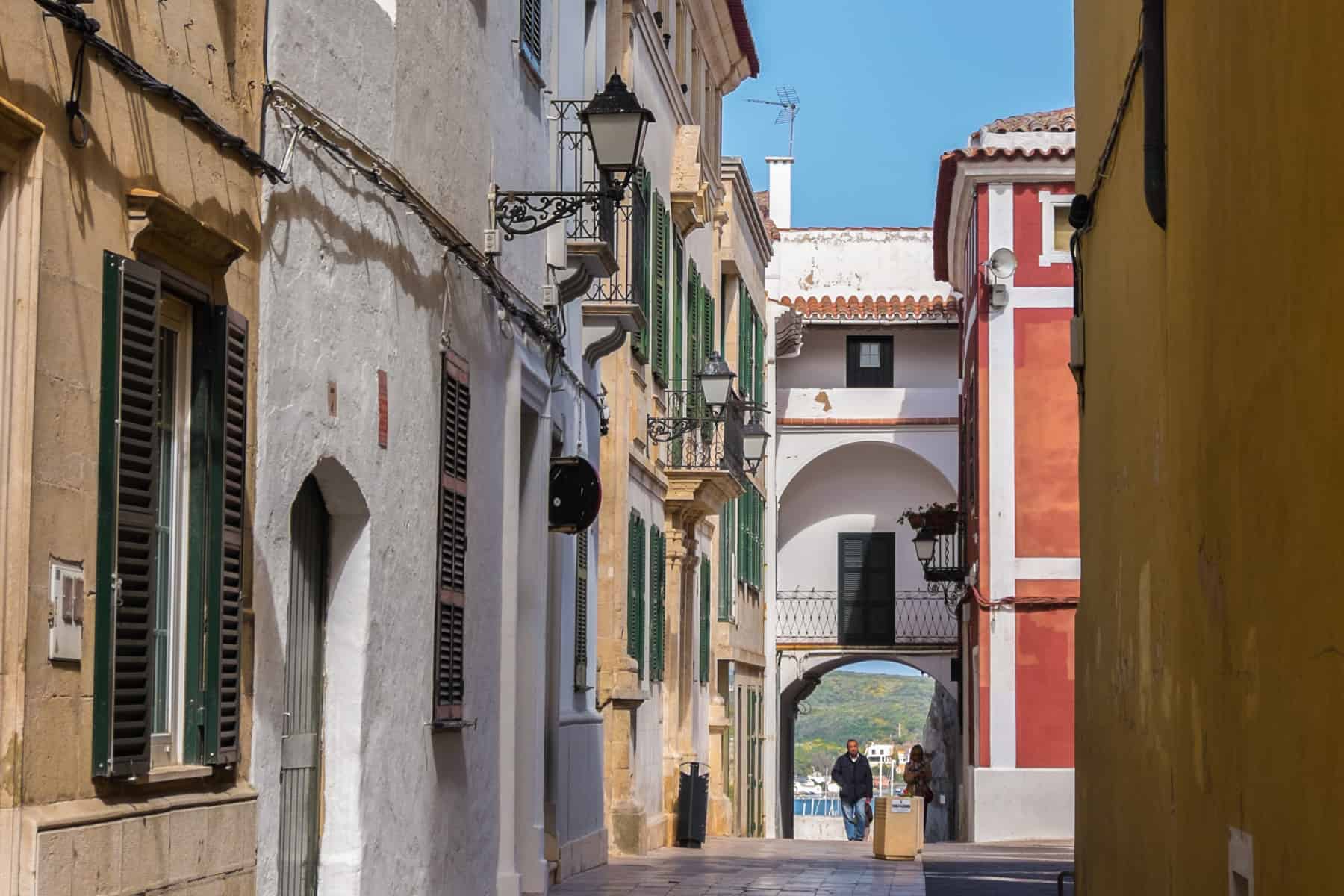 A street view in the town of Mahón, Menorca with houses painted white, yellow and red. 