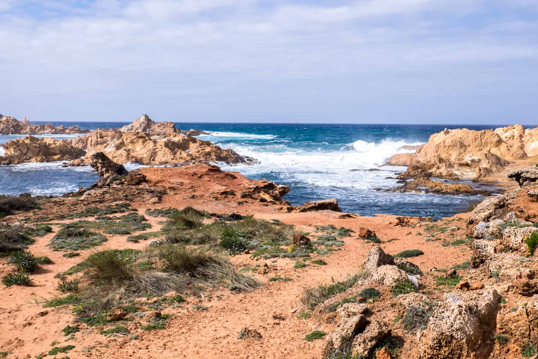 Crashing waves break on the golden rocky coastline of Menorca, Spain. 