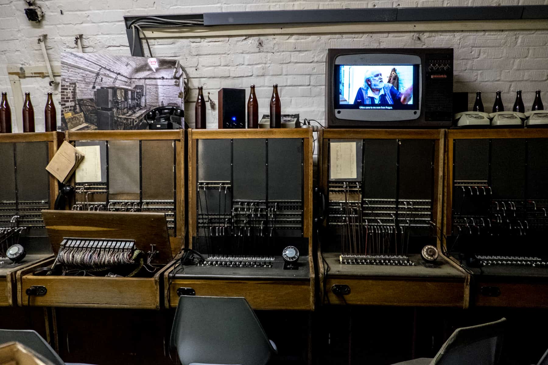 Old communications machines, wires and empty beer bottles in the 10-Z Bunker in Brno. A TV playing a video rests on top, as part of the exhibition. 