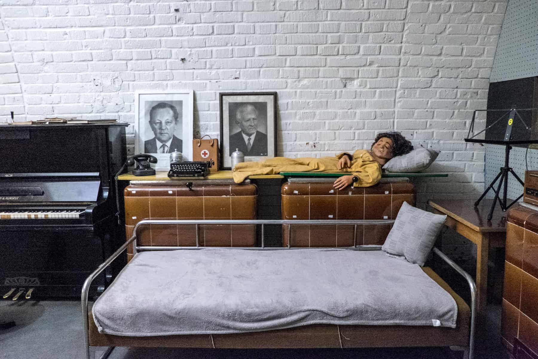 A piano, old brown furniture, black and white photos, a creepy doll in yellow dress and a metal bed with a white sheet - a selection of artefacts in the 10-Z bunker in Brno, Czech Republic. 