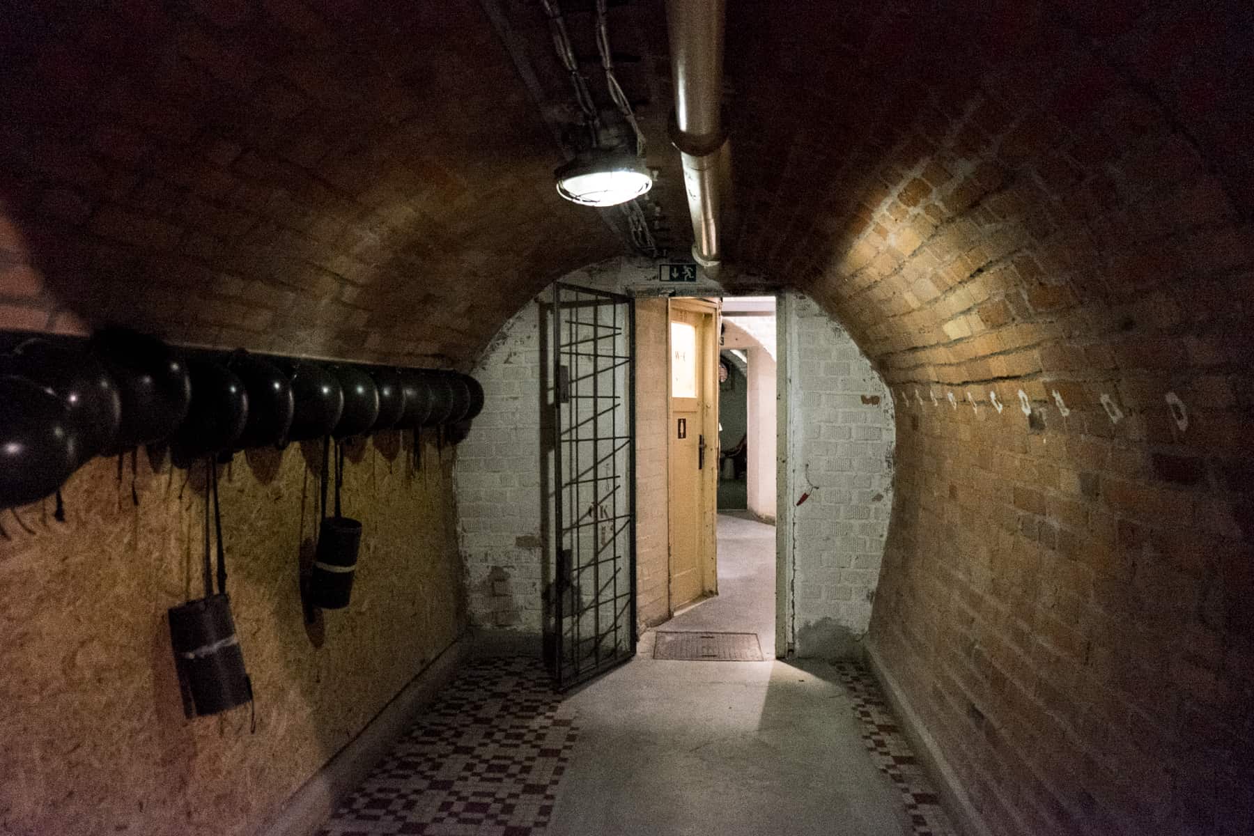 A circular brick-walled corridor lined with helmets leading to anther underground room in the Brno bunker. 