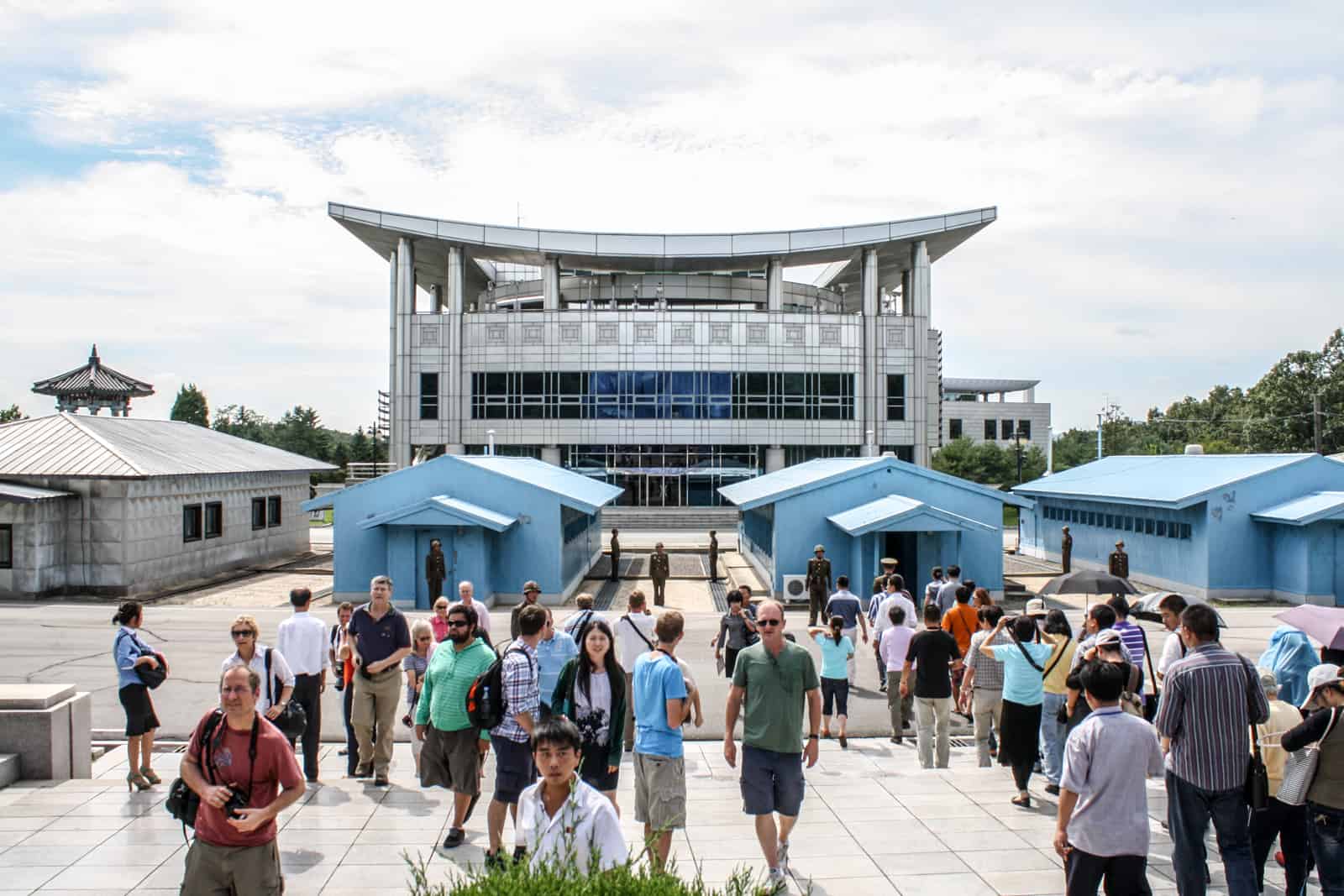 A group of travellers at the blue JSA huts facing the South Korean side on a DMZ tour in North Korea. 