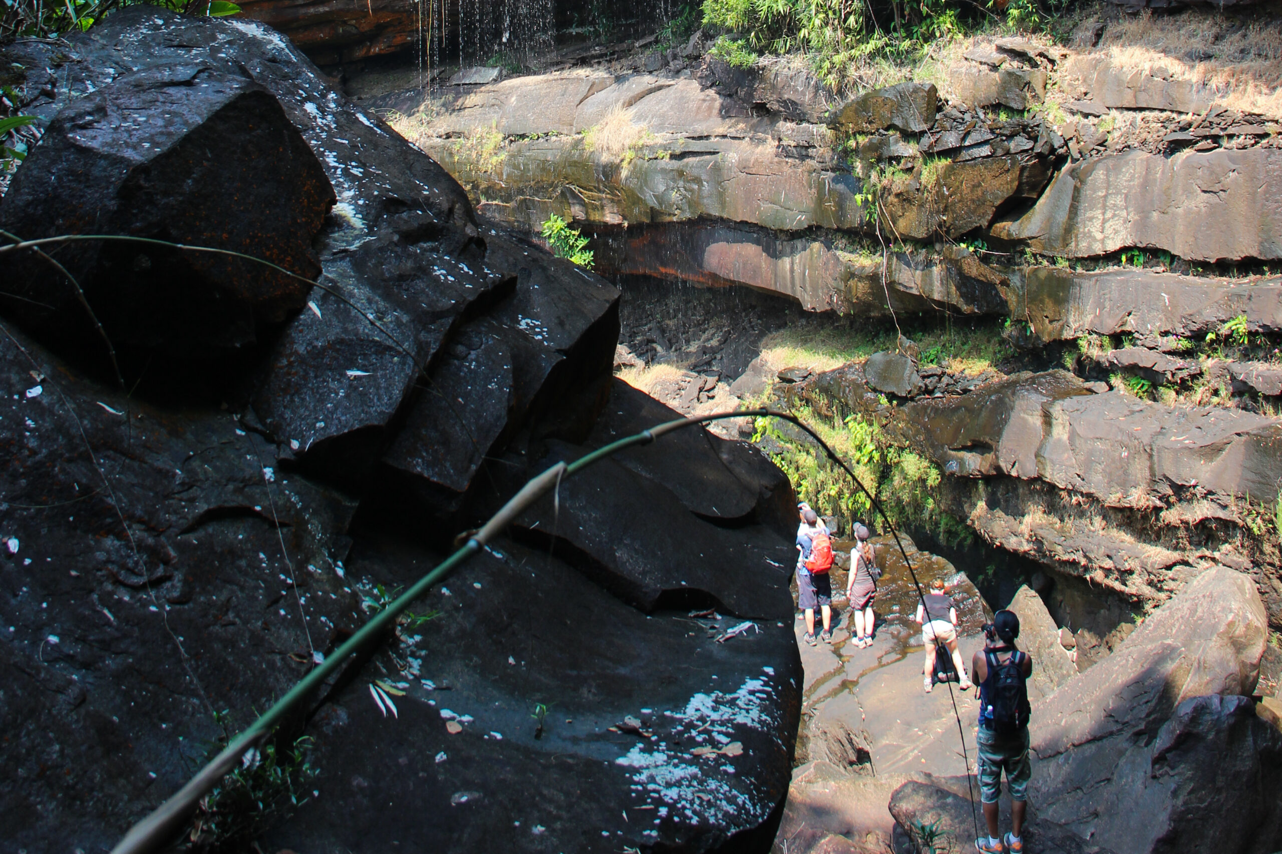 Four travellers trekking through large foliage covered rock caverns on Koh Kong island.