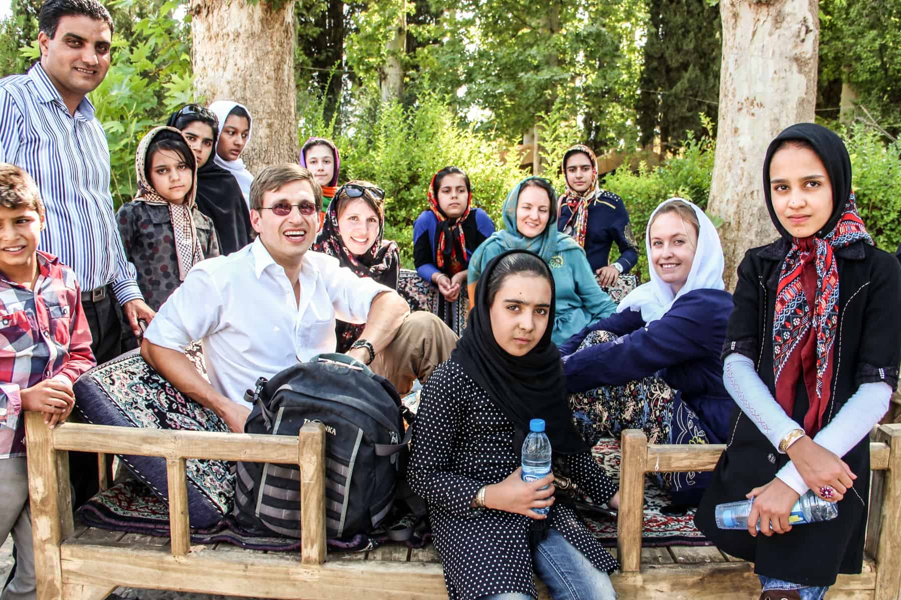Tourists in Iran sit with a group young Iranians for a group photo. 