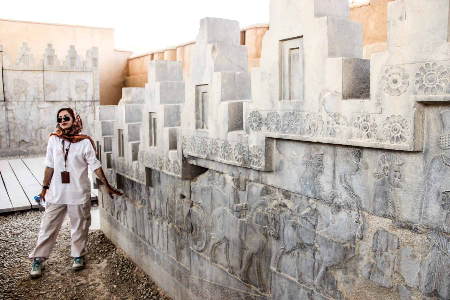 A female guide in Iran pointing to the ancient stone carvings at the Persepolis site in Iran.