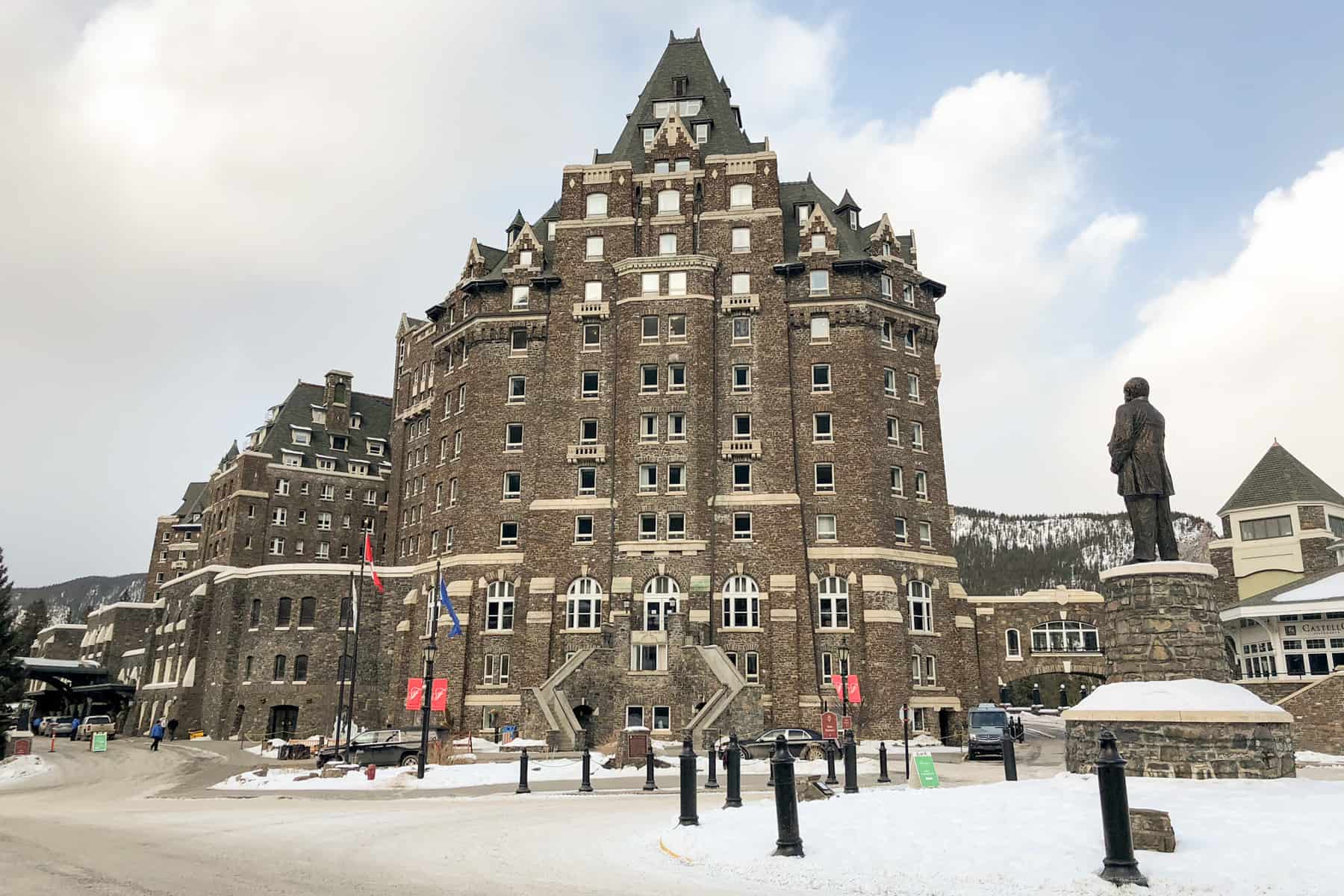 A large brown building with triangular top windows - the exterior of Fairmont Banff Springs Hotel in winter.