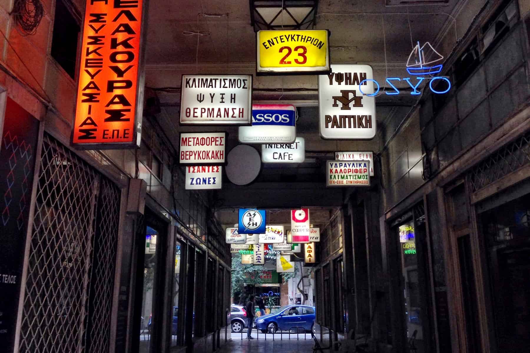An alleyway in Athens filled with old neon and lit signage hanging from the ceiling. 