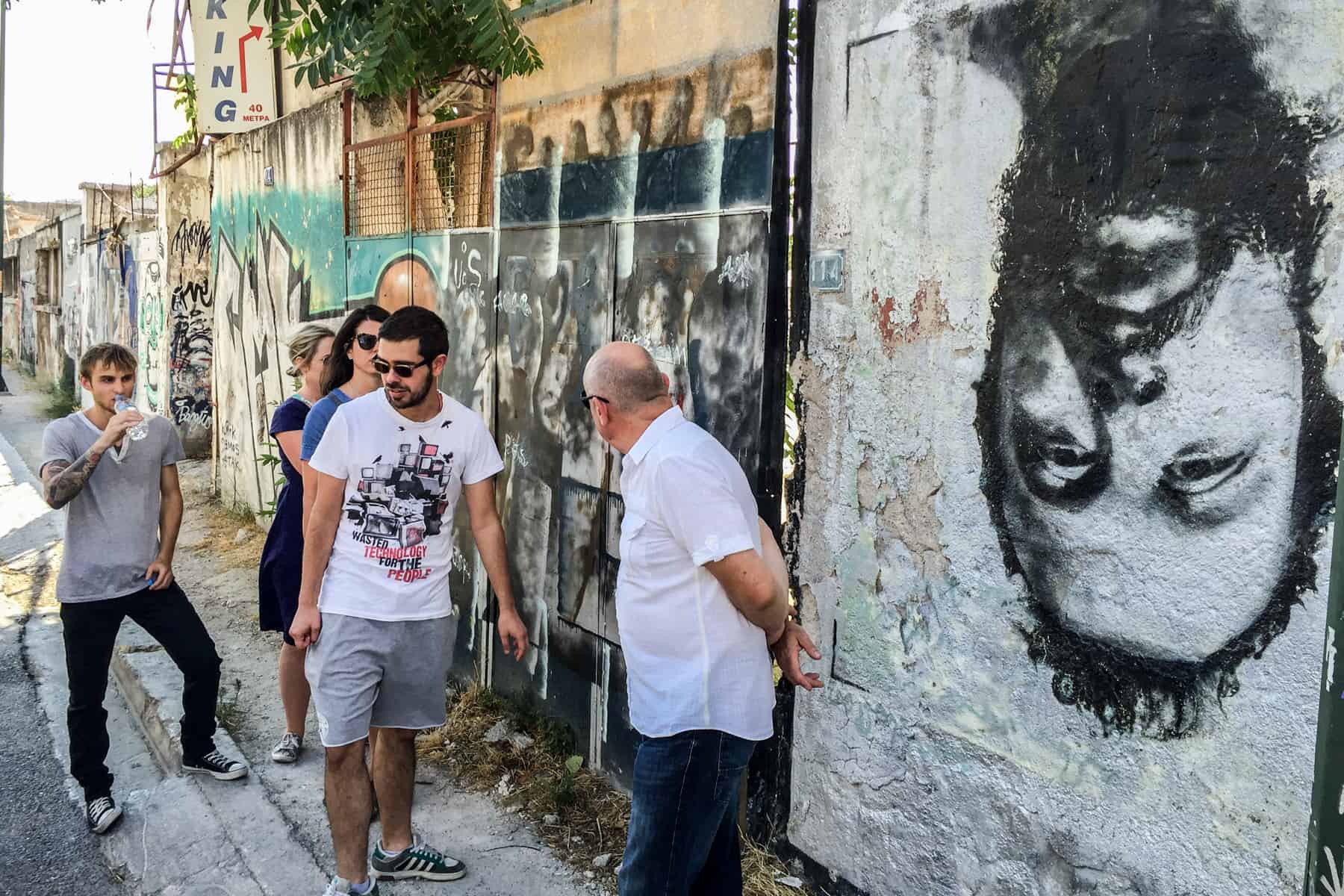 People looking at wall murals during an Athens street art walking tour.