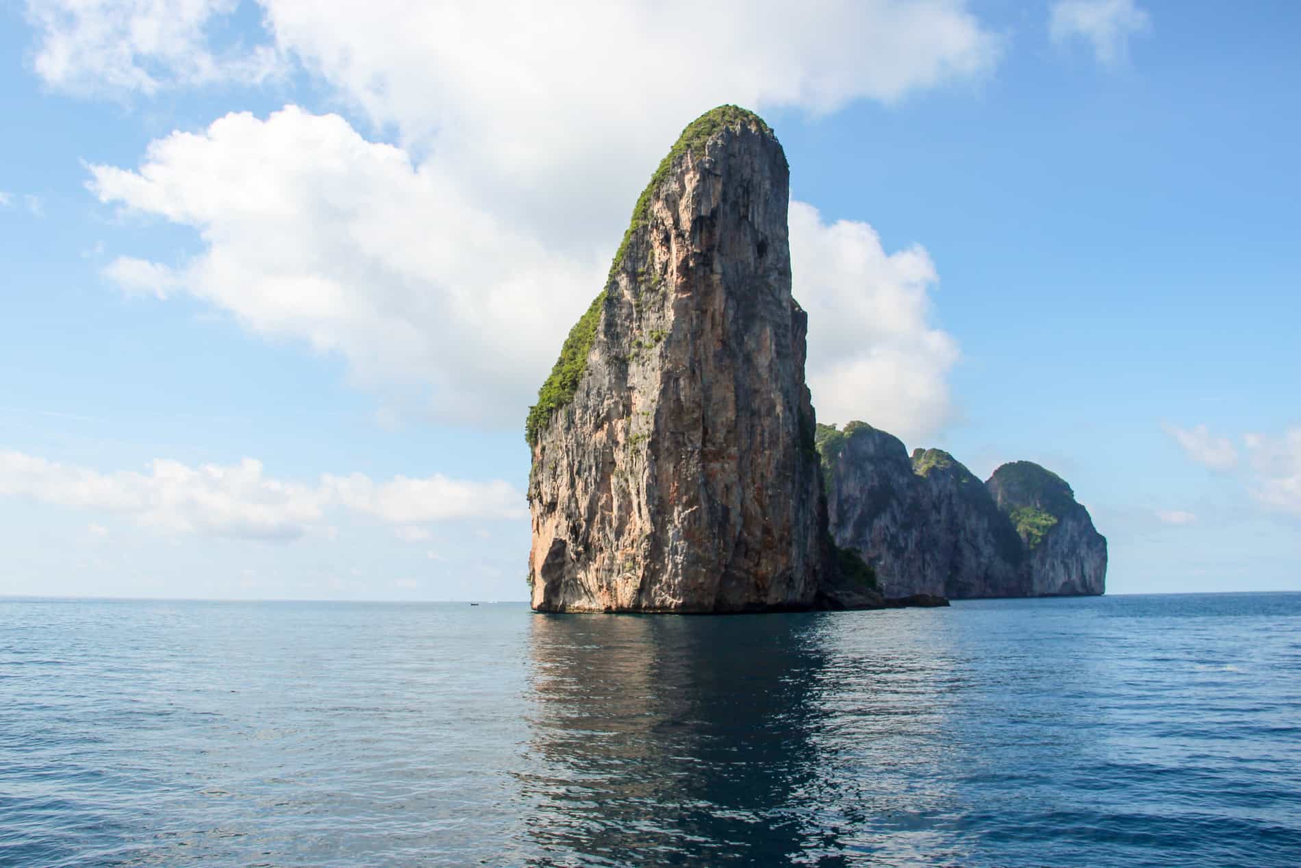 The grass covered, tall, rocky cliff face of Koh Phi Phi Leh island in Thailand where The Beach was filmed. 