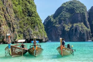 Wooden boats lined up in the cliff-backed turquoise waters at Maya Bay in Thailand.