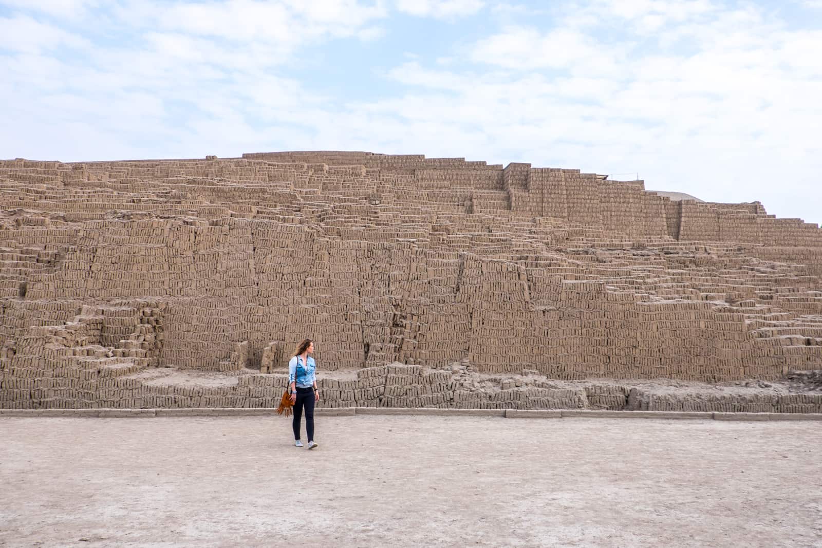 A woman walking in front of the sandy coloured stone Huaca Pucllana Inca Ruins in Lima, Peru. 