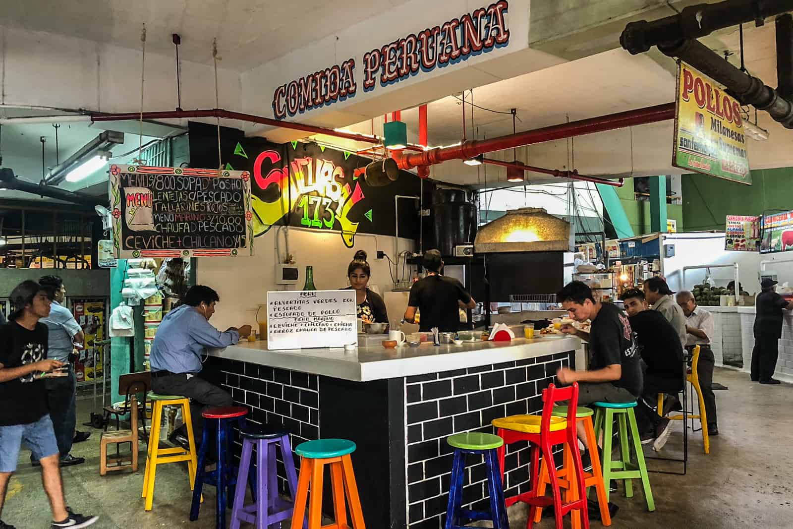 People sit around a Ceviche stall in a market in Lima, Peru.