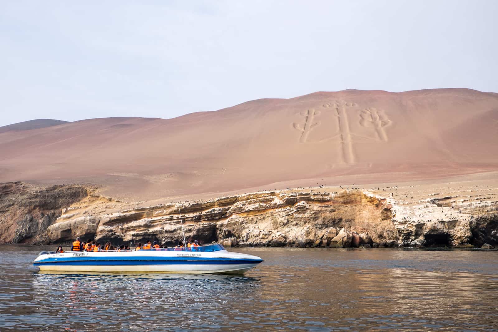 Peru sightseeing by boat to view the Paracas Candelabra carving in the rock hill in Ballestas Islands. 