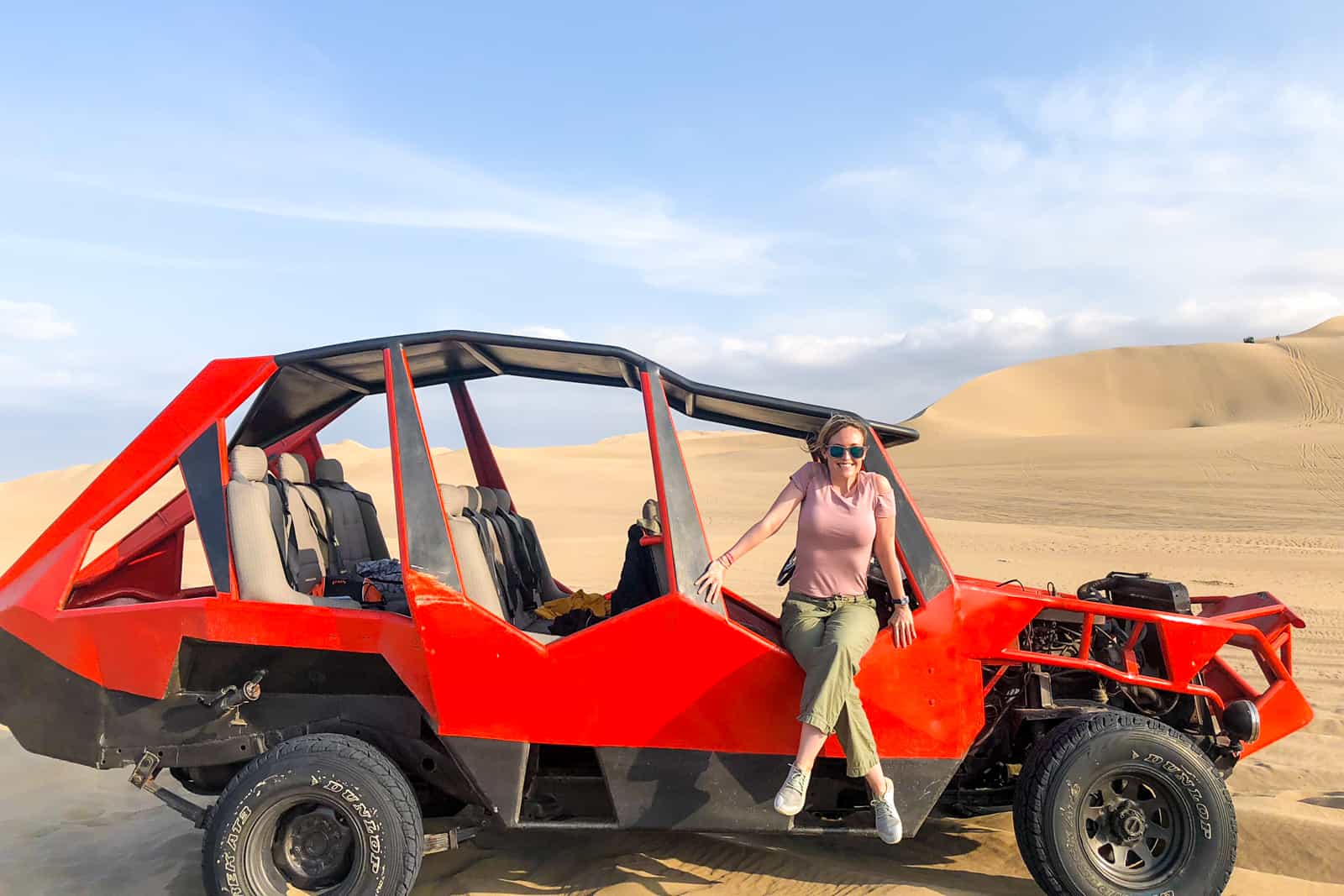 A woman sits on the red Sandbuggy parked on the Huacachina sand dunes in Peru.