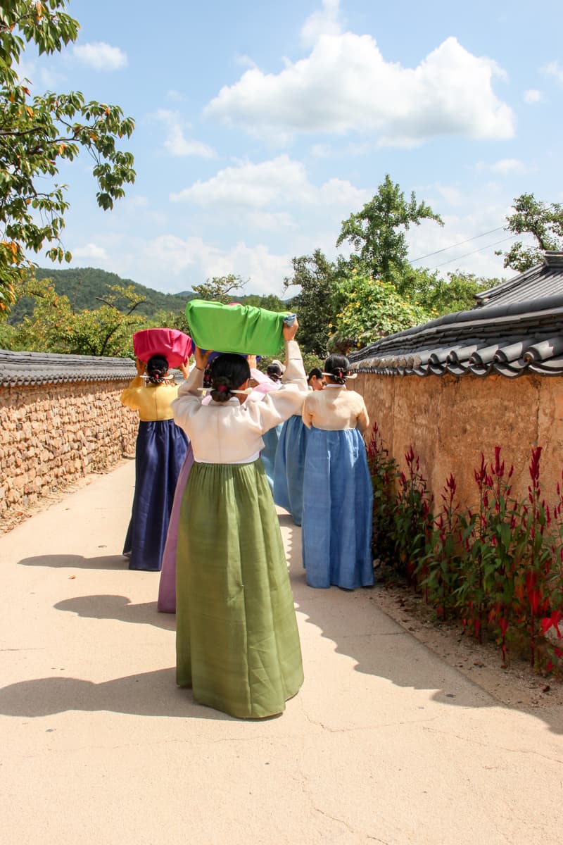 Korean women in traditional hanbok clothing walking through a traditional village in South Korea.