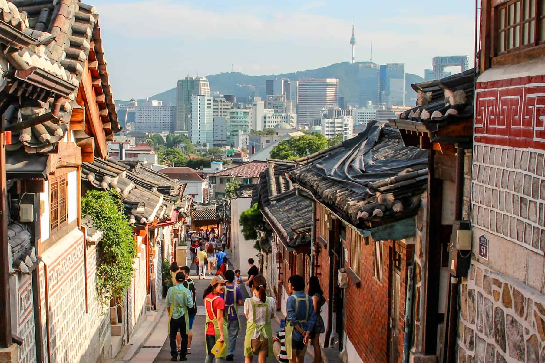 The Traditional Korean Bukchon Hanok Village on a hillside overlooking the modern skyline of Seoul. 