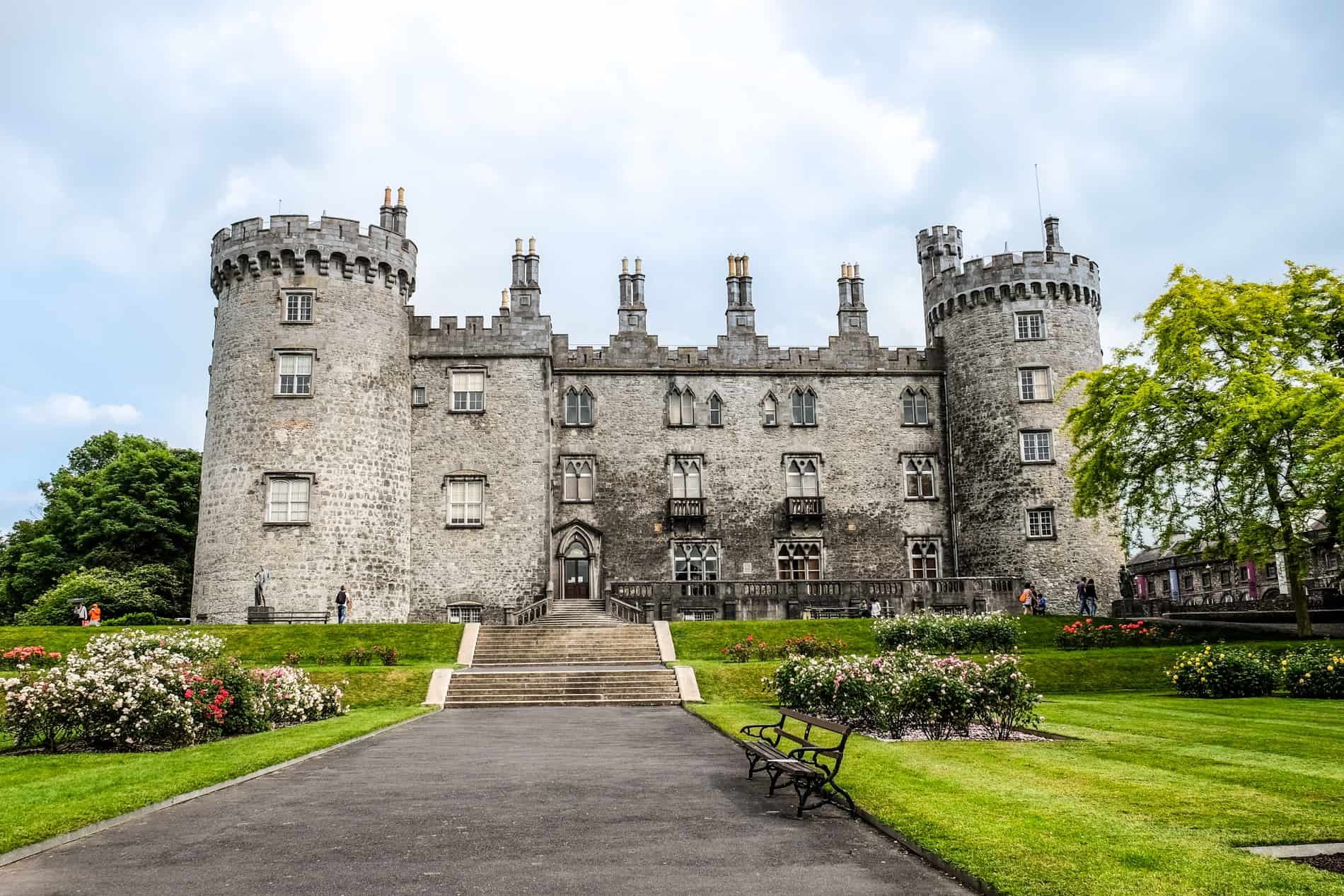 The silver stone Kilkenny Castle surrounded by manicured gardens. 