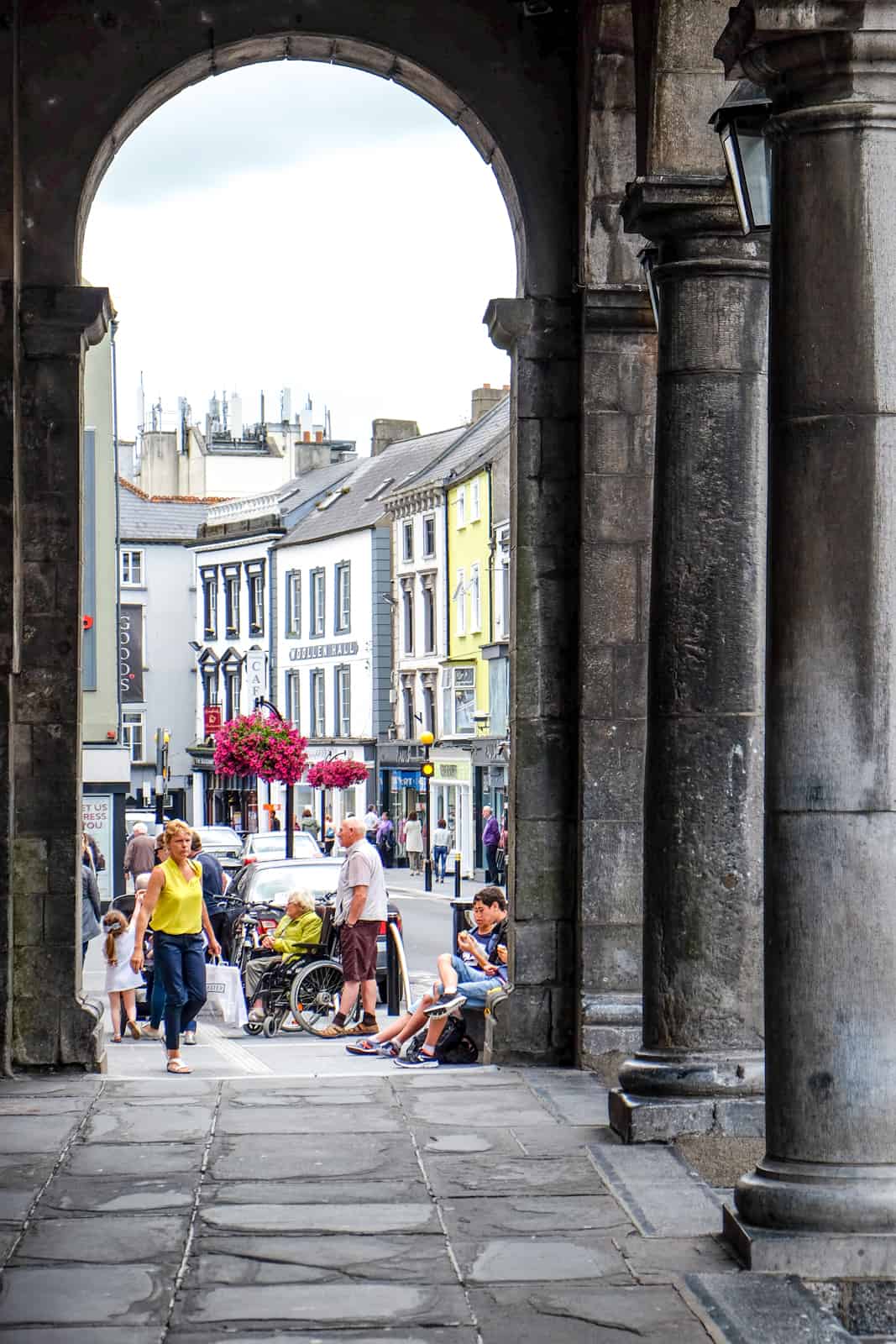 People in a stone archway in front of a row of houses on the Medieval Mile in Kilkenny. 