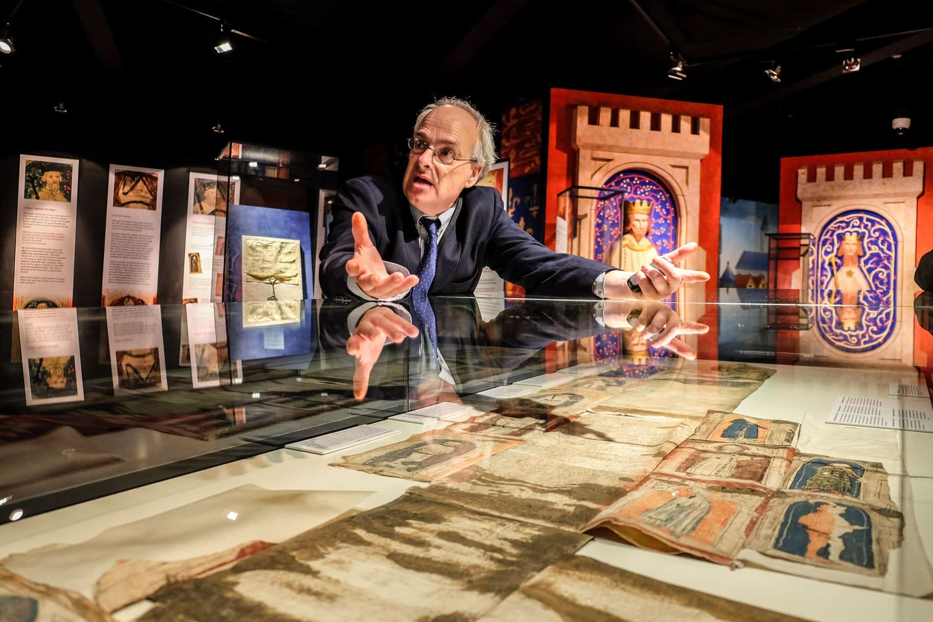 A curator leans on a glass cabinet explaining artefacts at the Medieval Museum in Waterford, Ireland.