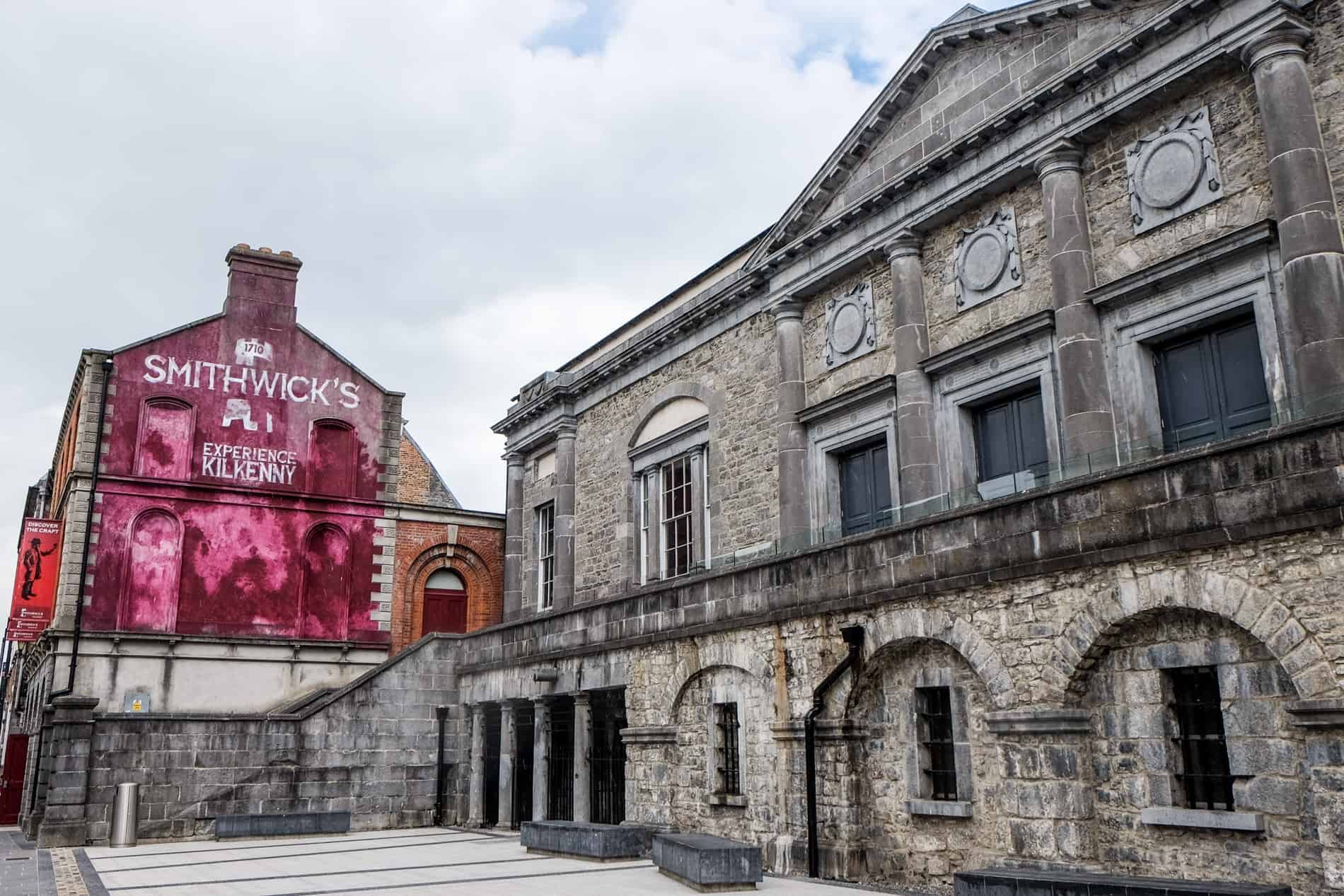 The old grey stone building of Smithwicks Brewery in Kilkenny with a painted pink wall. 